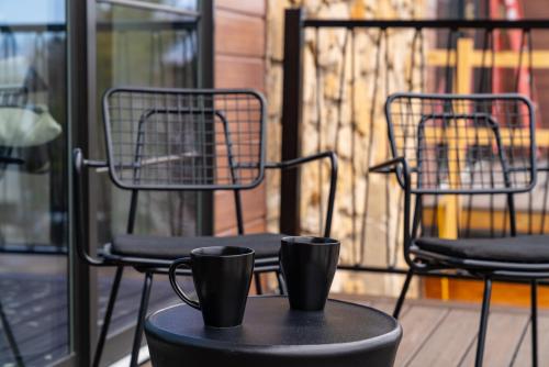 two chairs and cups on a table on a balcony at The Earl in Charlevoix in Charlevoix