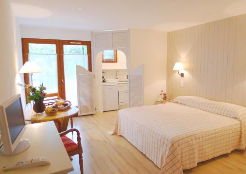 a hotel room with two beds and a desk with a television at La Pinède in Amélie-les-Bains-Palalda