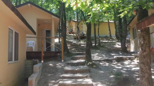 a house with trees in front of a yard at Ваканционно селище СБХ in Shkorpilovtsi