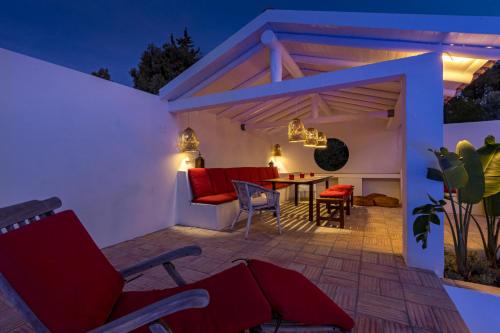 a patio with red chairs and a table at night at Villa AL Fresco in Guia