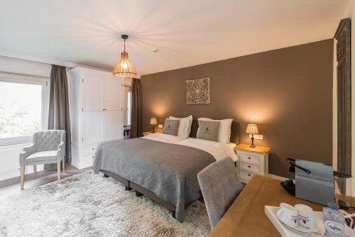 a bedroom with a bed and a desk and a table at Charmehotel Klokkenhof in Brasschaat