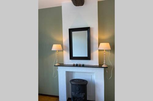 a room with a fireplace with two lamps and a mirror at Authentic Stays - 6p-apartment in Eijsden