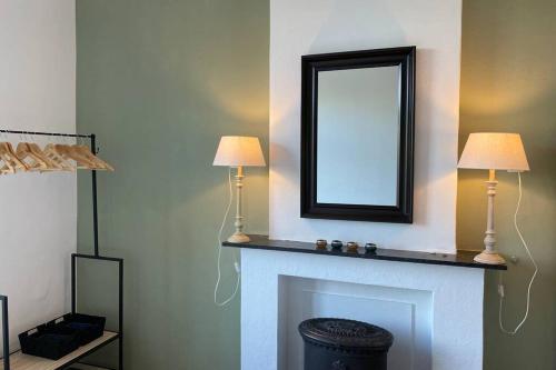 a living room with a fireplace with two lamps and a mirror at Authentic Stays - 6p-apartment in Eijsden