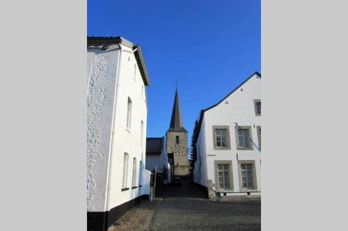 a street with two white buildings and a church at Authentic Stays - 6p-apartment in Eijsden