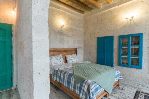 a bedroom with a bed in a room with blue windows at Atilla's Cave Hotel in Nevsehir