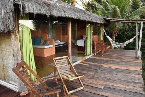 a deck with chairs and a hammock on a house at Art Jungle Eco Lodge in Itacaré