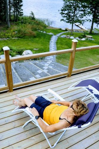 a woman laying in a chair on a deck at Hattapukki - Villa Himpula in Sysmä