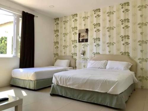 um quarto com 2 camas e uma janela em Summer Green Lodge em Kuantan