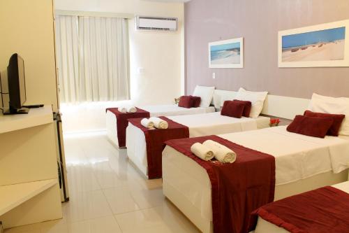 a hotel room with three beds and a television at San Phillip Flat Hotel in Fortaleza