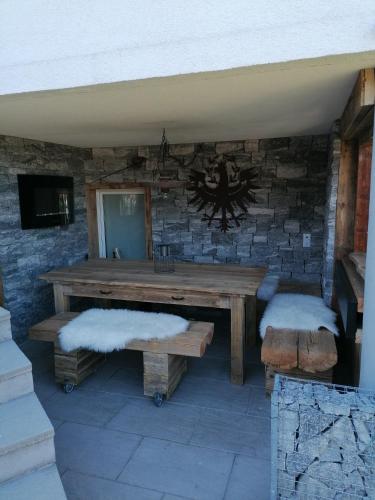 a wooden table and benches in a stone wall at Apart Schranz in Grins