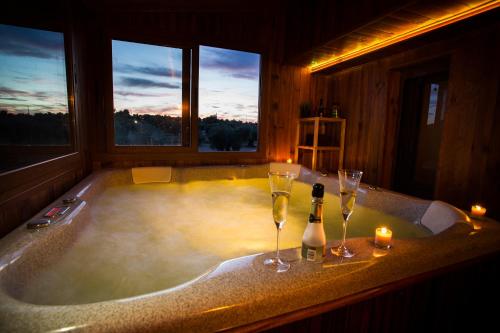 eine Badewanne mit Weingläsern, Weinflaschen und Kerzen in der Unterkunft Casa el Olivar de Don Pedro in Cobisa