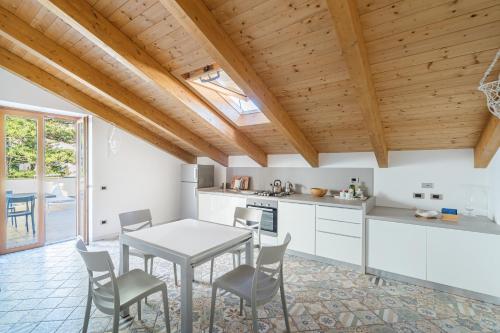 a kitchen with white cabinets and a table and chairs at Don Giulio Luxury Home jacuzzi in Vico Equense