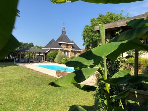 une maison avec une piscine dans une cour dans l'établissement Maison d'Hôtes Lassaubatju, à Hontanx