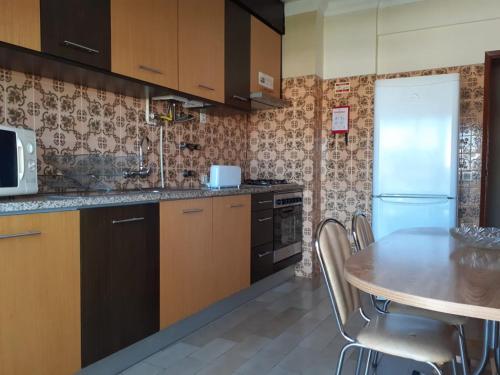 a kitchen with a table and a refrigerator at SEIA Alojamentos Leitao in Seia