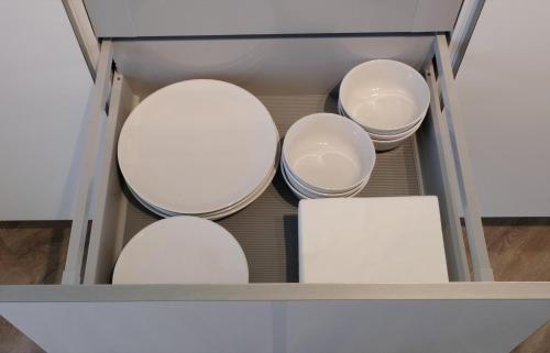 four white bowls in a drawer in a cabinet at Beautiful 60m2 One-Bedroom Apartment with Terrace - WA7A in Tiel