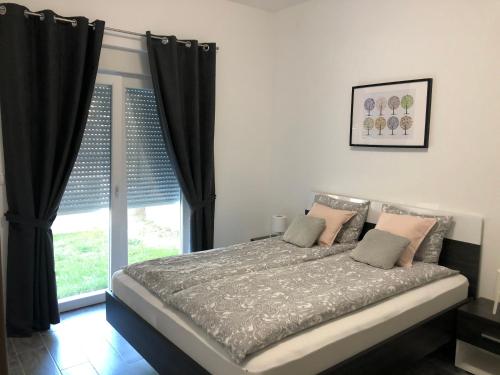a bedroom with a bed with black curtains and a window at Apartman Spring in Sombor