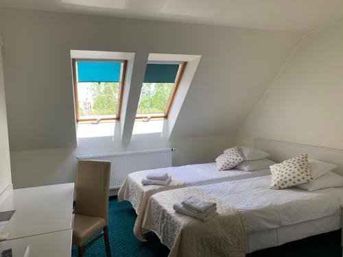 a room with two beds and a chair and two windows at Hotel Court Wellness&Spa in Kędzierzyn-Koźle