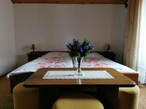 a table with a vase of flowers on it with a bed at Apartment Žvab in Bohinj