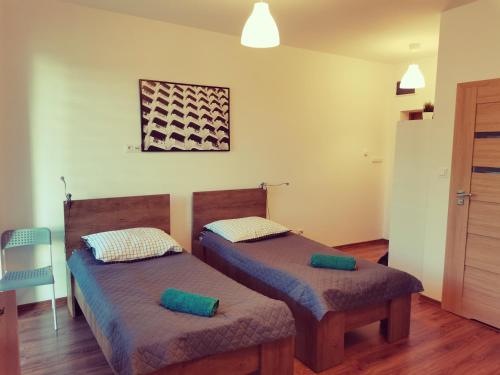 2 łóżka pojedyncze w pokoju z drewnianą podłogą w obiekcie Dworcowa 10D w mieście Płock