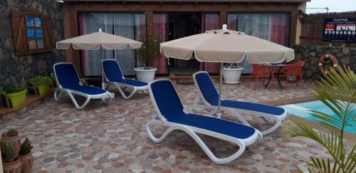 a group of chairs and umbrellas on a patio at Villa FranyMar in Lajares