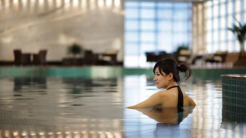 a woman sitting in the water in a swimming pool at Crowne Plaza Yantai Sea View by IHG in Yantai
