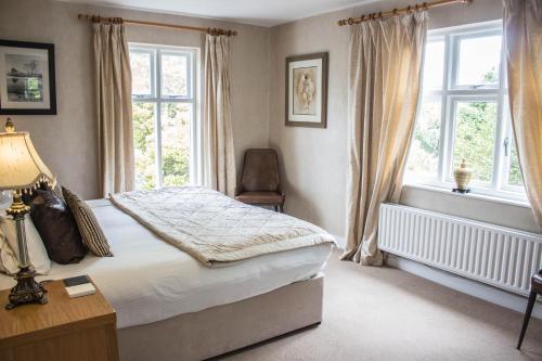 a bedroom with a bed and a chair and windows at The Howbeck & The Retreat Central location, incl off-site Health Club and parking EV point available, GREAT DEALS ON in Windermere