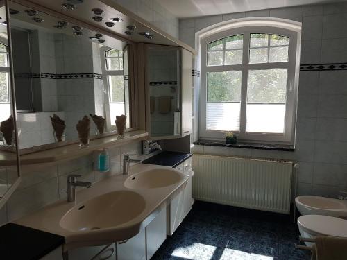 a bathroom with two sinks and a mirror at Ringhotel Villa Margarete in Waren