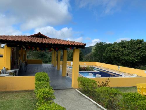 een geel huis met een zwembad in een tuin bij Flat em Serra Negra - PE - Condomínio Próximo Bodega de Véio, shows e eventos in Bezerros