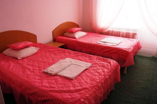 two beds in a room with red sheets and pillows at Kyiv Hotel in Poltava