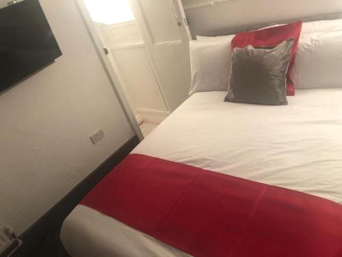 a bedroom with a bed with a red and white blanket at Kirubash Central Pier Hotel in Blackpool