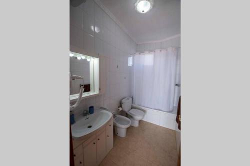 a bathroom with a toilet and a sink and a toilet istg at Atico en la Playa de La Aldea. in San Nicolás