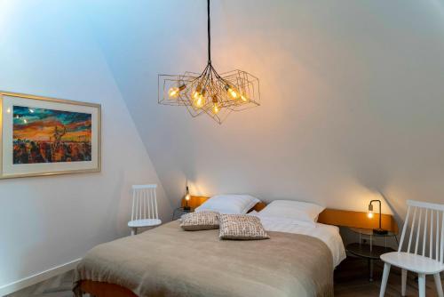 1 dormitorio con 1 cama con 2 sillas y una lámpara de araña en B&W Holiday Apartments, en Grubbenvorst