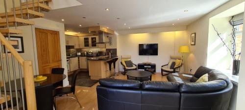 a living room with a leather couch and a kitchen at The Old Pump House in Tenby