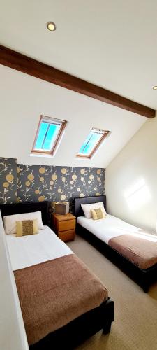 two beds in a room with two windows at The Old Pump House in Tenby
