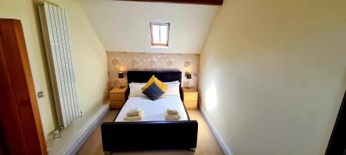 a small bedroom with a bed with yellow and blue pillows at The Old Pump House in Tenby