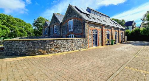 a brick building with a stone wall in front of it at The Old Pump House in Tenby