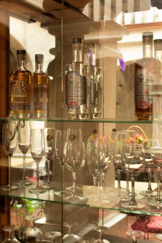 a bunch of wine glasses on a shelf with bottles at Hotel Boutique Casa Catrina in Oaxaca City