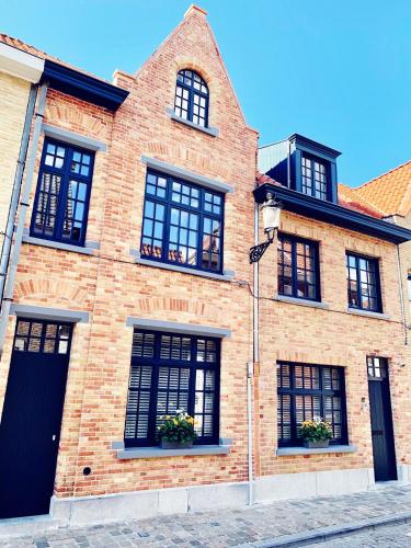 un edificio de ladrillo con ventanas negras en una calle en B&B Marie-J of Bruges, en Brujas