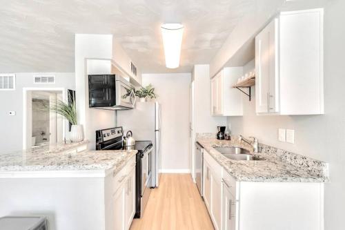 a white kitchen with white cabinets and marble counter tops at Global Cup The Munger Proper - Spa Pool in Dallas