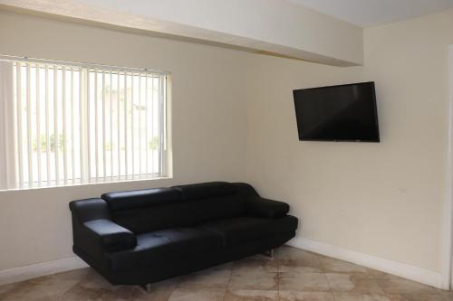a black leather couch in a living room with a flat screen tv at Curtis Inn & Suites in Hollywood