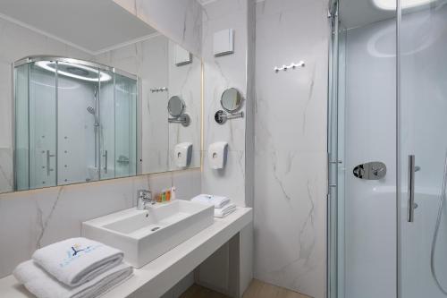 a white bathroom with a sink and a shower at Lydia Maris Resort & Spa in Kolimbia