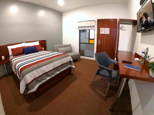 サカテカスにあるホテル プロビデンシアのベッドルーム1室(ベッド1台、デスク、椅子付)