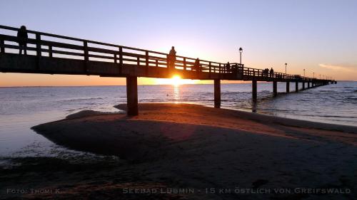 a pier with people walking on it near the ocean at Zimmervermietung Koltermann in Greifswald