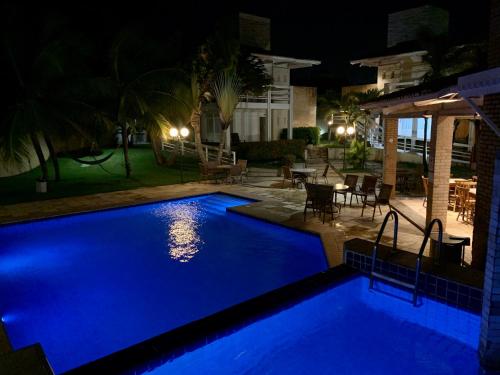 a large blue swimming pool at night with a patio at Pousada Tropical Ilhas in Aquiraz