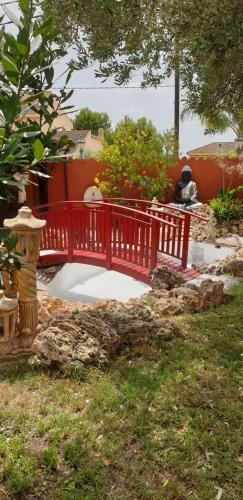 a red bridge over a pond in a garden at Hotel Iris La Eliana in La Eliana