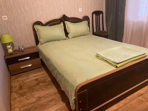 a bedroom with a bed with a wooden headboard and a table at Golden Gate in Akhaltsikhe