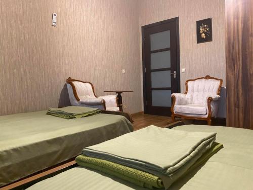 a room with two beds and two chairs and a door at Golden Gate in Akhaltsikhe
