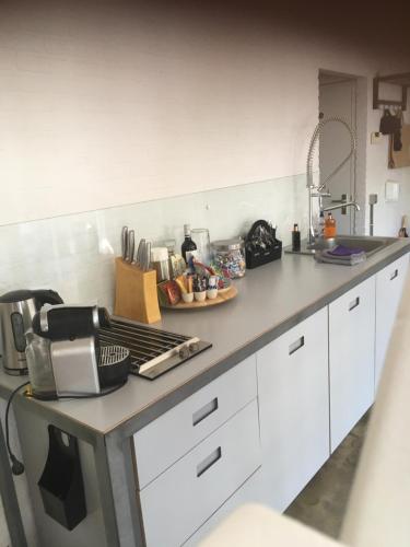 a kitchen with white cabinets and a counter top at Gardenhouse with private jacuzzi & private sauna in Teteringen