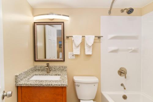 W łazience znajduje się umywalka, toaleta i lustro. w obiekcie Glenwood Springs Inn w mieście Glenwood Springs