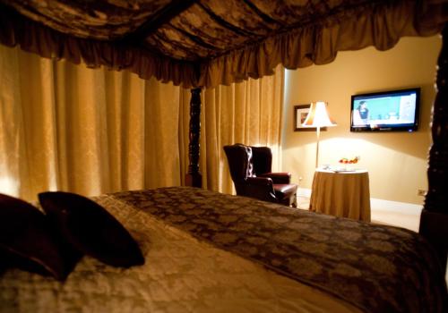 a bedroom with a bed and a chair and a television at Westenra Arms Hotel in Monaghan
